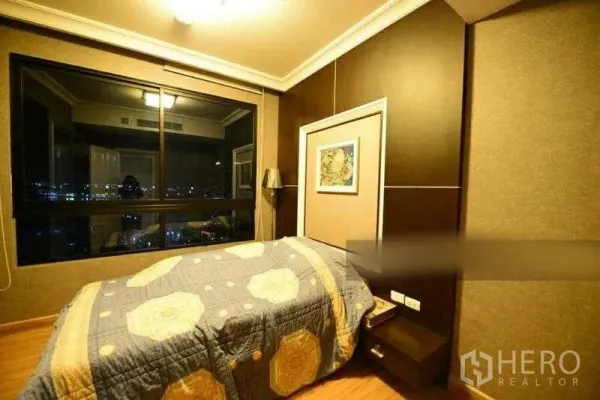 Condominium for rent in Bang Kho Laem, Bangkok - Second bedroom with warm wood flooring and wide window showcasing city night views.