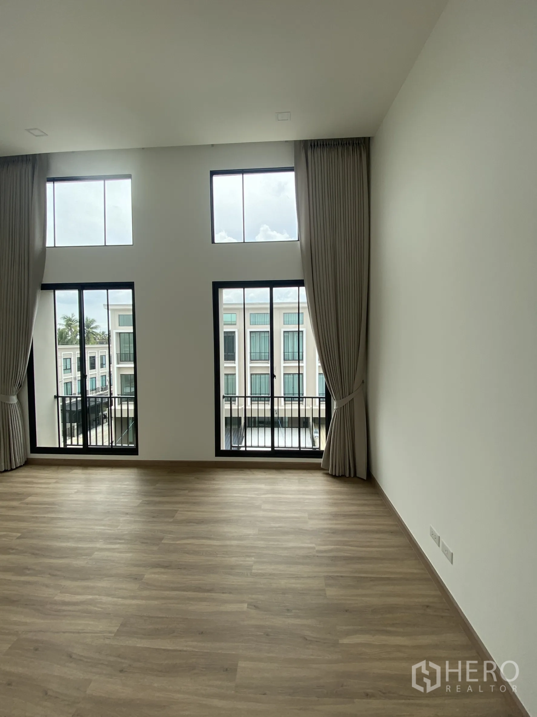 Townhouse for rent or sale in Bang Khae, Bangkok - Bright room from another angle showing paired windows and balcony railings