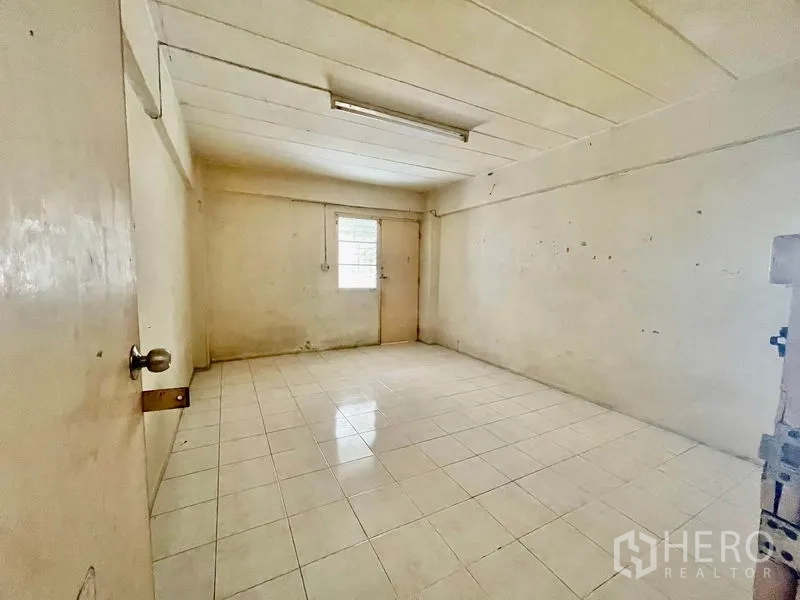 Apartment for sale in Mueang Samut Prakan, Samut Prakan - Empty tiled room with a small window and fluorescent ceiling light.
