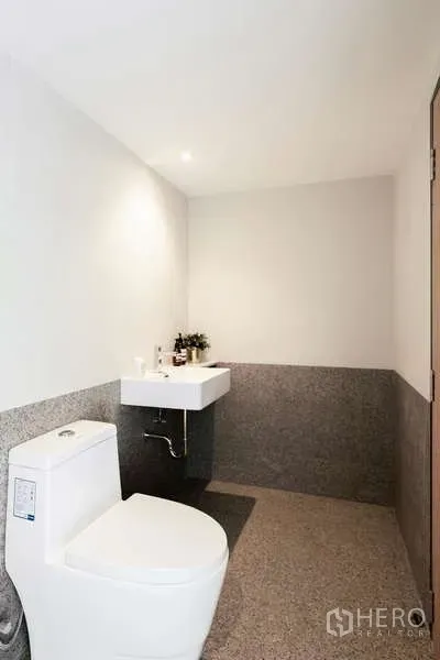Office Space for rent in Watthana, Bangkok - Modern restroom with white sink and toilet and grey stone wall finish.