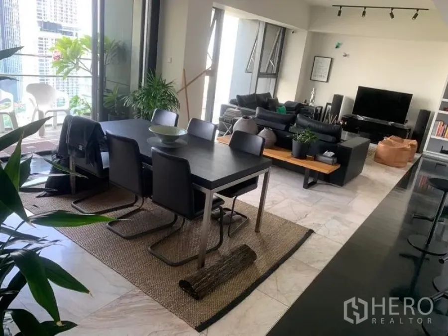 公寓 出售在Sathon, Bangkok - 开放式客餐厅连接城市景观阳台，黑色餐桌与室内绿植。