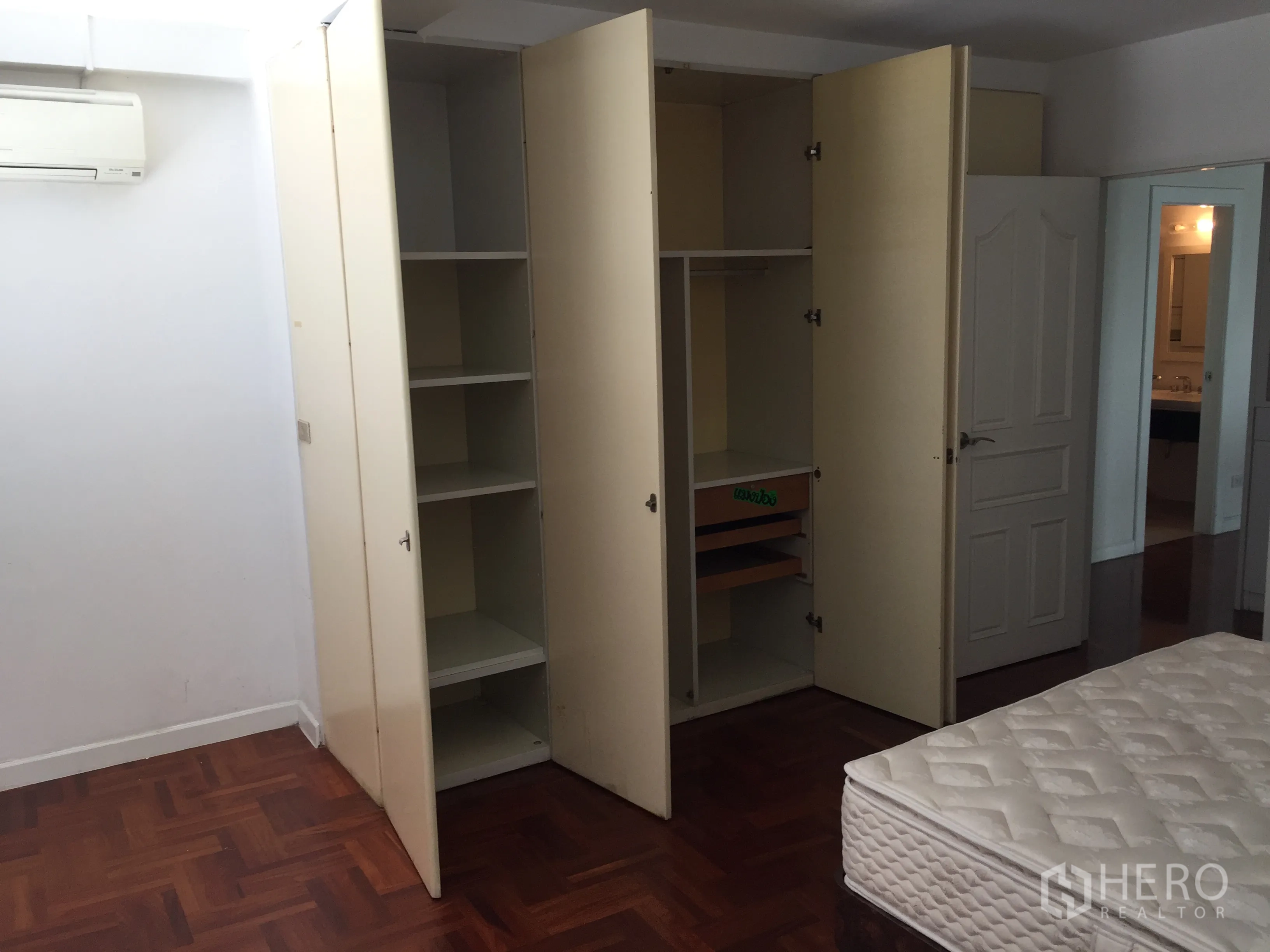 Condominium for rent in Sathon, Bangkok - Bedroom showing open built-in wardrobes, parquet floor and doorway leading to the ensuite bathroom.