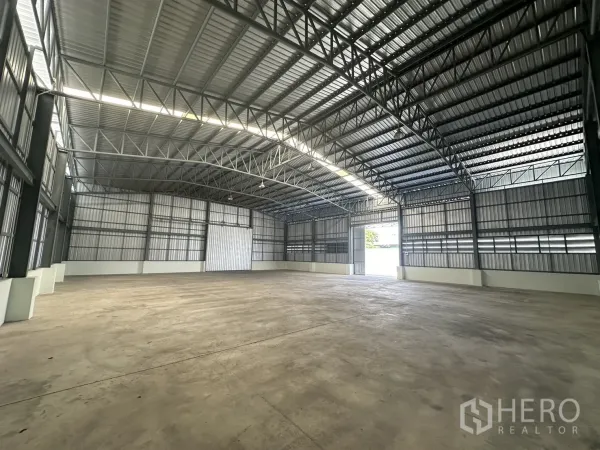 Warehouse for rent in Mueang Pathum Thani, Pathum Thani - Open-plan warehouse interior featuring high steel truss roof, skylight strip and smooth concrete floor.