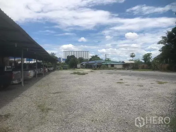 Warehouse for sale in Rayong - Large gravel parking area with covered carports beside the site.
