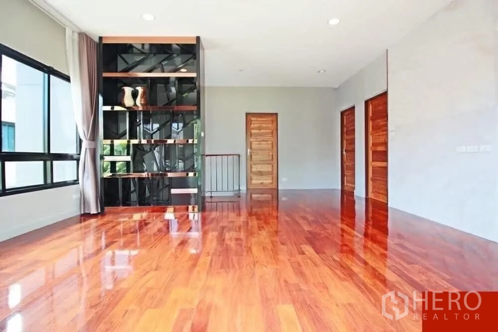 Detached House for rent in Bang Khae, Bangkok - Spacious family area with polished hardwood floors and a stylish built‑in shelving unit.