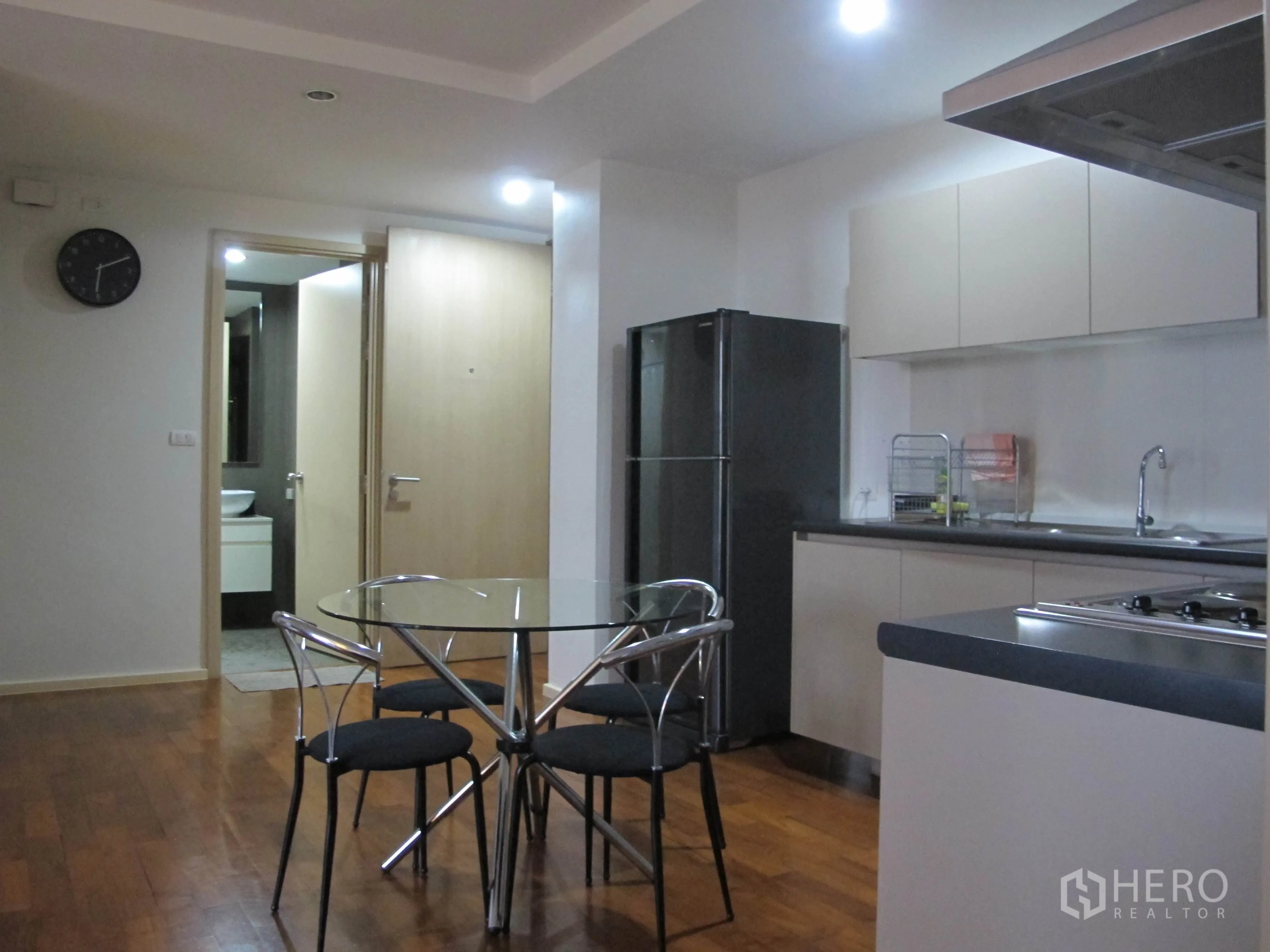公寓 出租在Khlong Toei, Bangkok - 明亮的餐厨区，玻璃餐桌、高门冰箱，通向浴室的门廊。