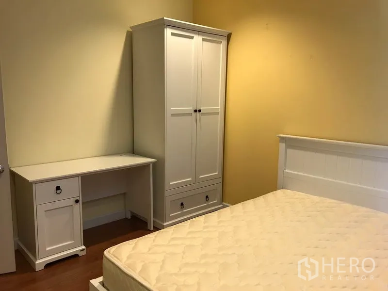 Townhouse for rent in Wang Thonglang, Bangkok - Third bedroom corner with white wardrobe and desk adjacent to the bed frame.