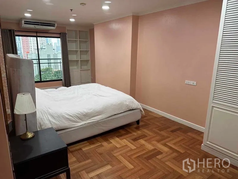 公寓 出售在Bangkok - 卧室另一个角度，衣柜、木地板与宽窗外的天际线。