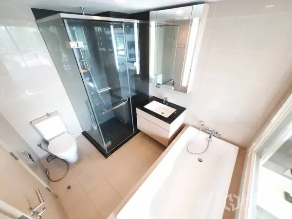 Condominium for rent in Watthana, Bangkok - Modern bathroom featuring glass shower, separate bathtub by the window, vanity, and toilet.