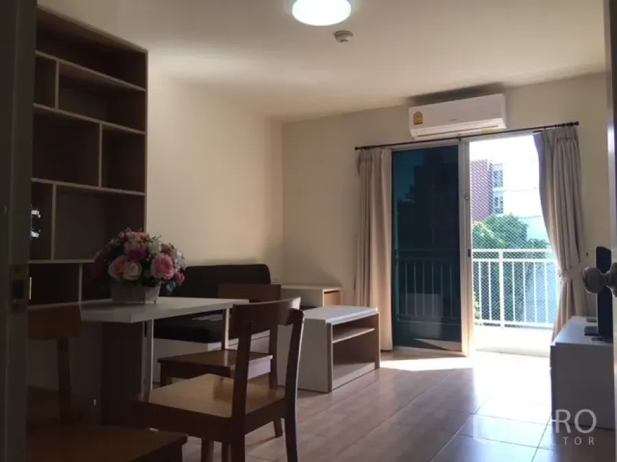 Condominium for rent in Phra Khanong, Bangkok - Bright living and dining area with wood floors, air conditioner, and sliding door to a sunny balcony.