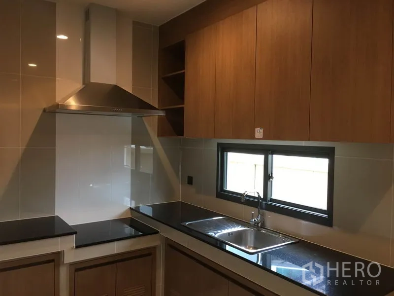 บ้าน ให้เช่าในBang Kapi, Bangkok - ครัวปิดสไตล์โมเดิร์น ท็อปดำ ตู้ไม้ และเครื่องดูดควัน