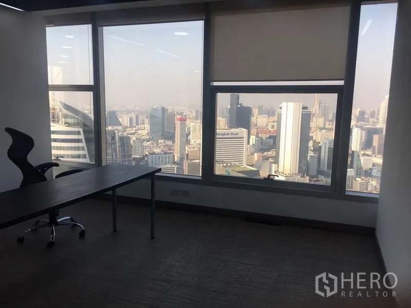 Office Space for rent in Sathon, Bangkok - Private office desk beside large windows showcasing panoramic city views with roller blinds.