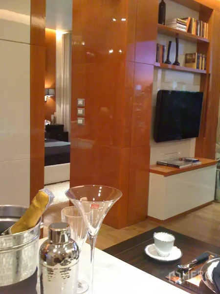 คอนโด ให้เช่าหรือขายในKhlong Toei, Bangkok - พื้นที่นั่งเล่นแบบเปิดผนังลายไม้เงา ชั้นวางบิลท์อิน ทีวีติดผนัง และเคาน์เตอร์บาร์พร้อมแก้ว