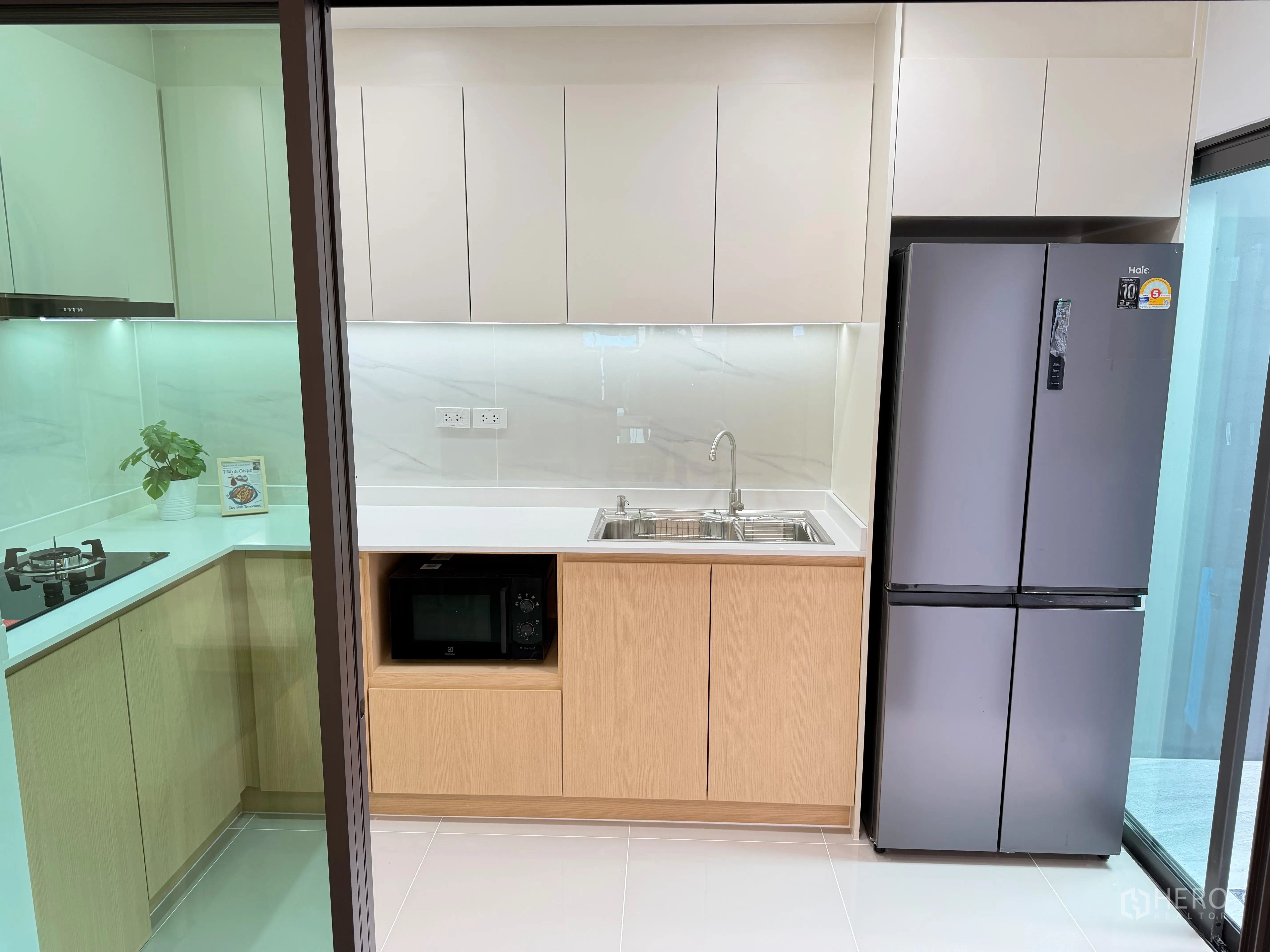 Townhouse for rent in Bang Phli, Samut Prakan - Modern kitchen with cabinets, sink, fridge, and sliding glass door.
