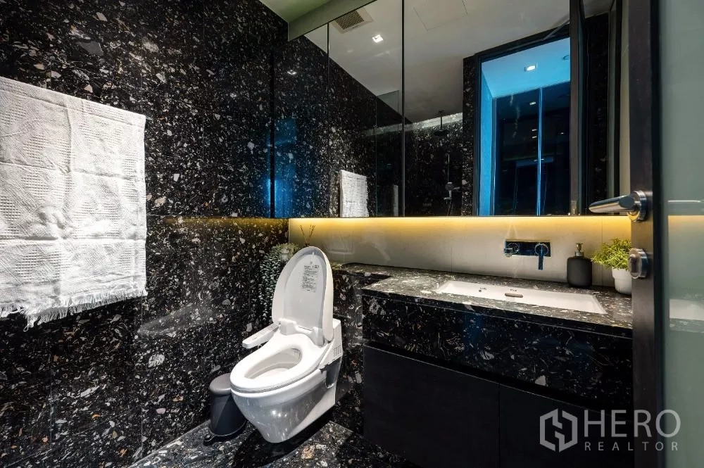 公寓 出租或出售在Khlong Toei, Bangkok - 豪华浴室，黑色大理石墙、背光洗手台与现代坐便器。