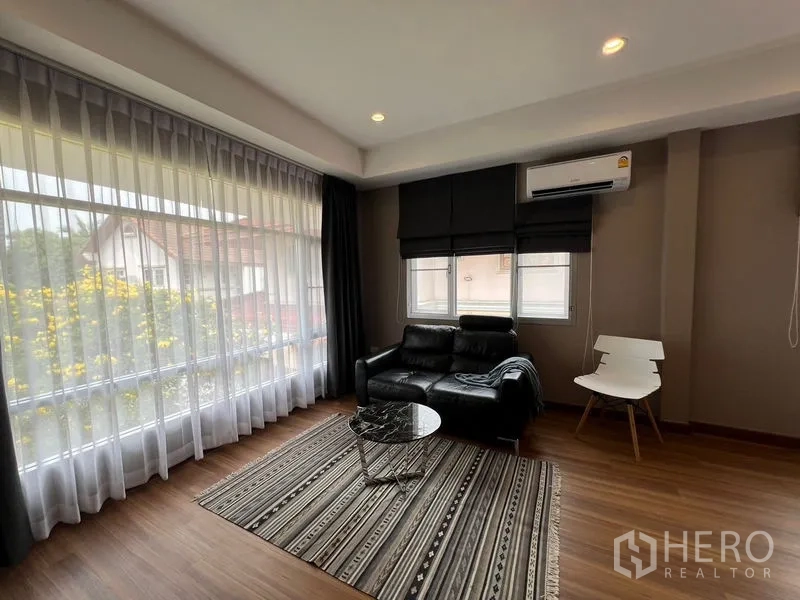 Detached House for sale in Mueang Pathum Thani, Pathum Thani - Upstairs lounge with corner windows, blackout blinds and black leather sofa.
