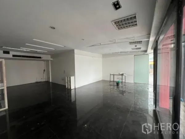 零售空间 出租在Watthana, Bangkok - 宽敞的店铺，临街大窗与磨砂玻璃门旁的小桌。