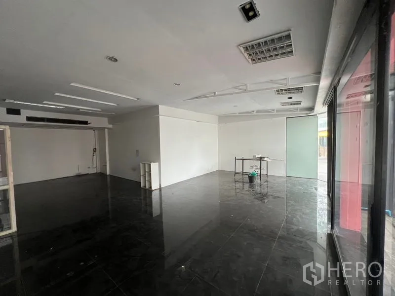 零售空间 出租在Watthana, Bangkok - 宽敞的店铺，临街大窗与磨砂玻璃门旁的小桌。