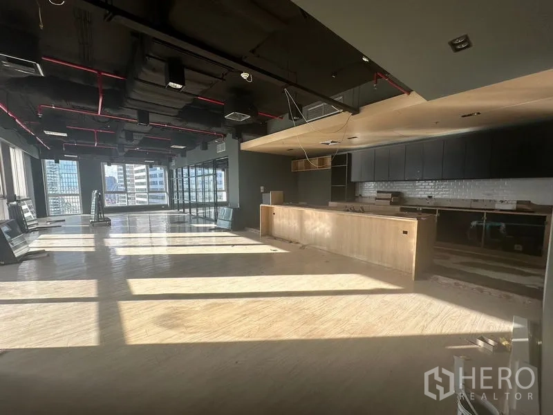 Office Space for rent in Bang Rak, Bangkok - Sunlit open‑plan office with modern pantry, exposed ceiling and skyline views.
