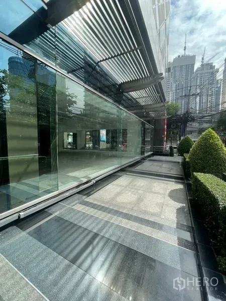 พื้นที่ขายปลีก ให้เช่าในWatthana, Bangkok - ทางเดินภายนอกอาคาร ผนังกระจกหลังคาระแนงโลหะ พร้อมพุ่มไม้ตัดแต่งกลางเมือง