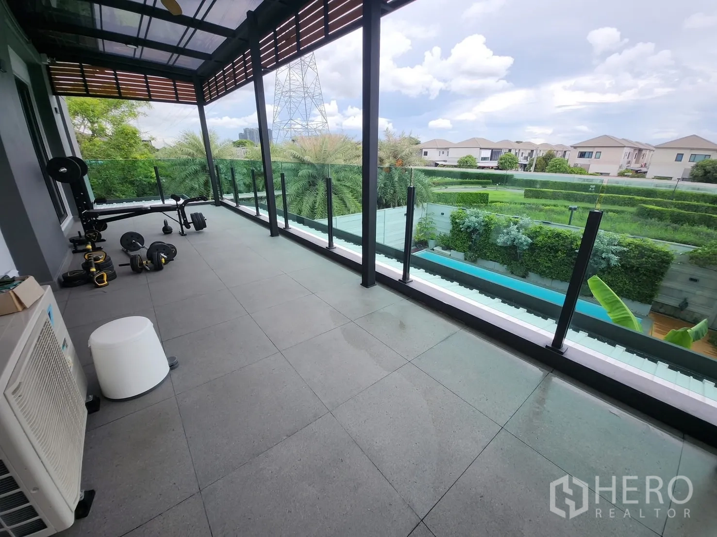Detached House for rent in Bang Phli, Samut Prakan - Long covered balcony with glass railing set up as a home gym overlooking the garden.