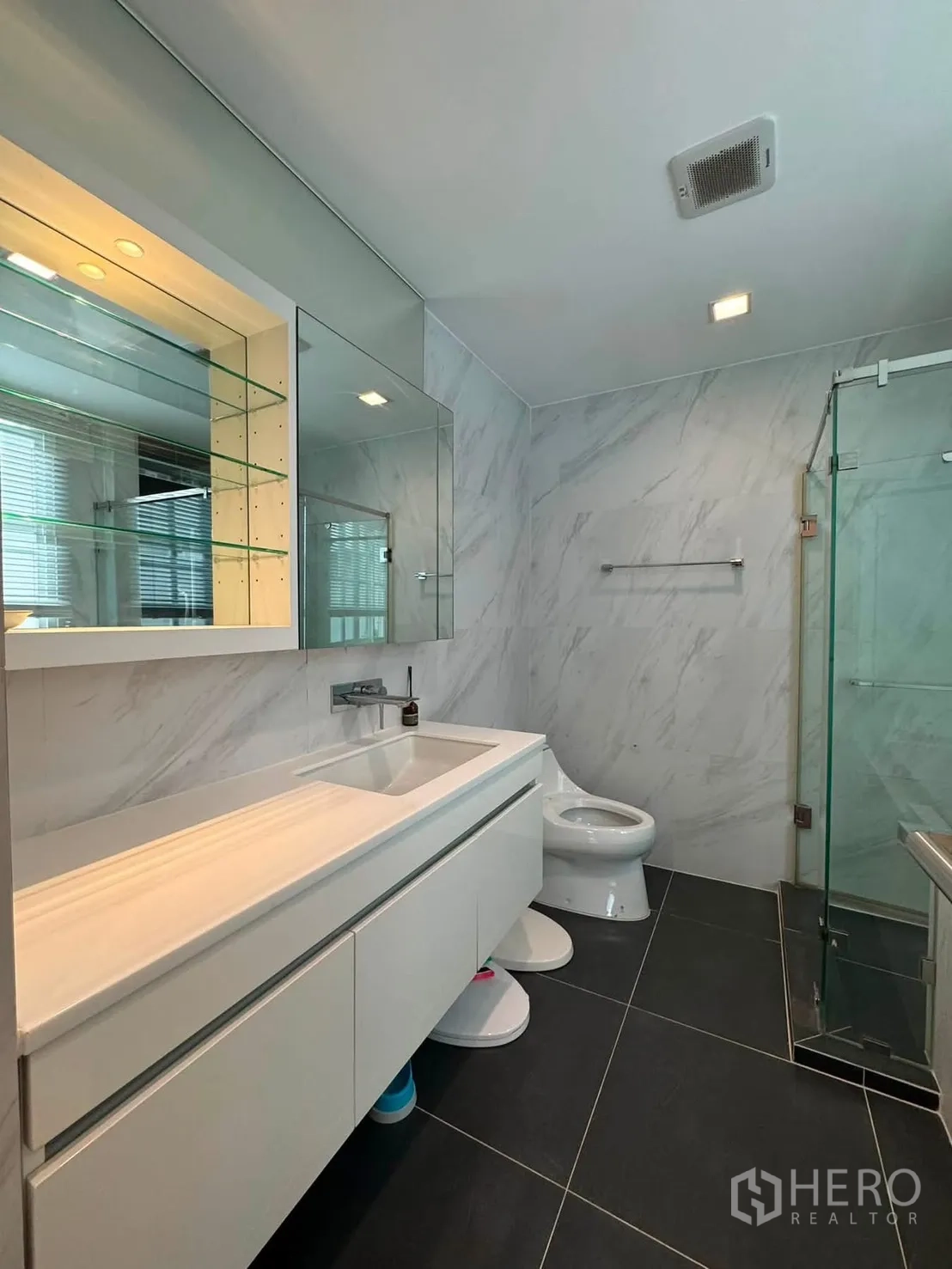 Townhouse for rent in Lat Phrao, Bangkok - Bathroom with long countertop vanity, mirrors and a glass shower.