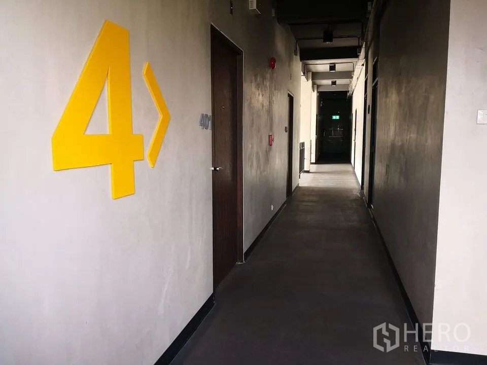 สำนักงาน ให้เช่าในPhra Khanong, Bangkok - โถงทางเดินชั้น 4 ตัวเลขสีเหลืองบนผนัง ประตูไม้ และไฟเพดานสไตล์ลอฟท์