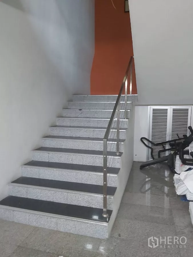 Warehouse for rent in Krathum Baen, Samut Sakhon - Ground‑floor staircase with metal railing beside stored equipment.