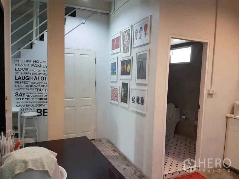 店屋 出售在Bang Rak, Bangkok - 走廊挂满装饰画，旁有瓷砖卫生间入口