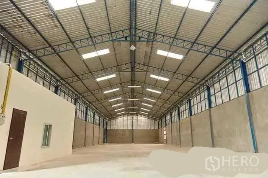 Factory for rent in Mueang Nakhon Pathom, Nakhon Pathom - Spacious factory interior with high steel truss roof, skylights, polished concrete floor and a side office room.