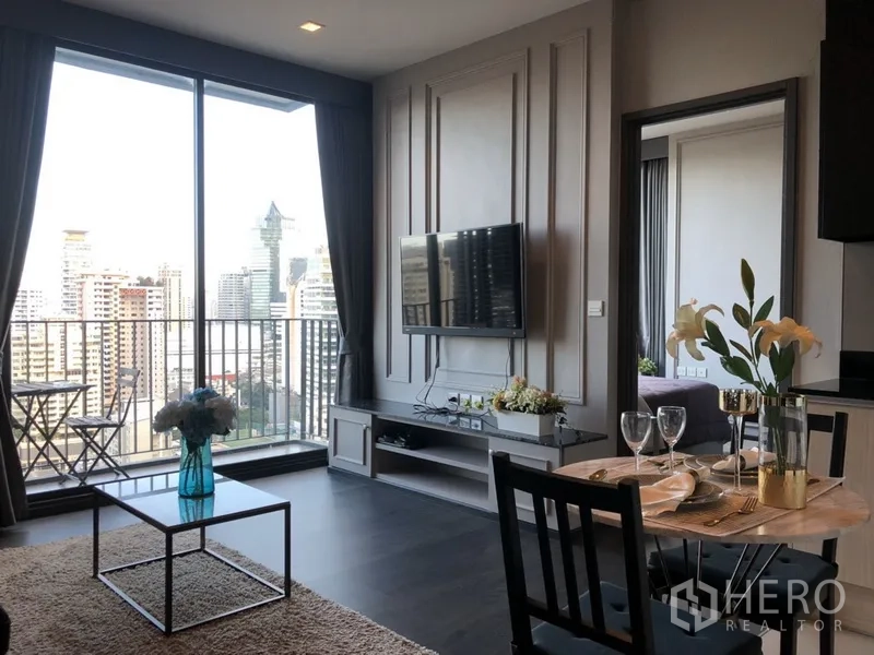 คอนโด ให้เช่าในWatthana, Bangkok - ห้องนั่งเล่นมีหน้าต่างเต็มบาน ระเบียงพร้อมชุดโต๊ะ มองเห็นสกายไลน์ พร้อมทีวีติดผนังและชั้นวาง