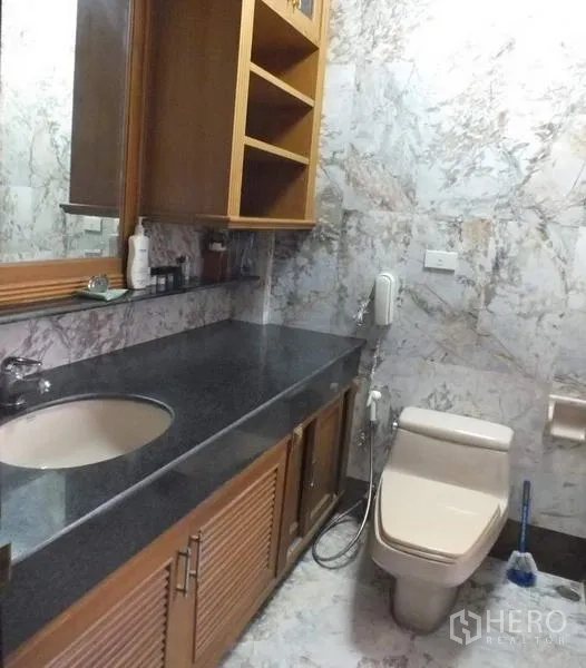 Detached House for rent in Bang Rak, Bangkok - Bathroom with marble-patterned walls, long dark granite vanity, sink and toilet.