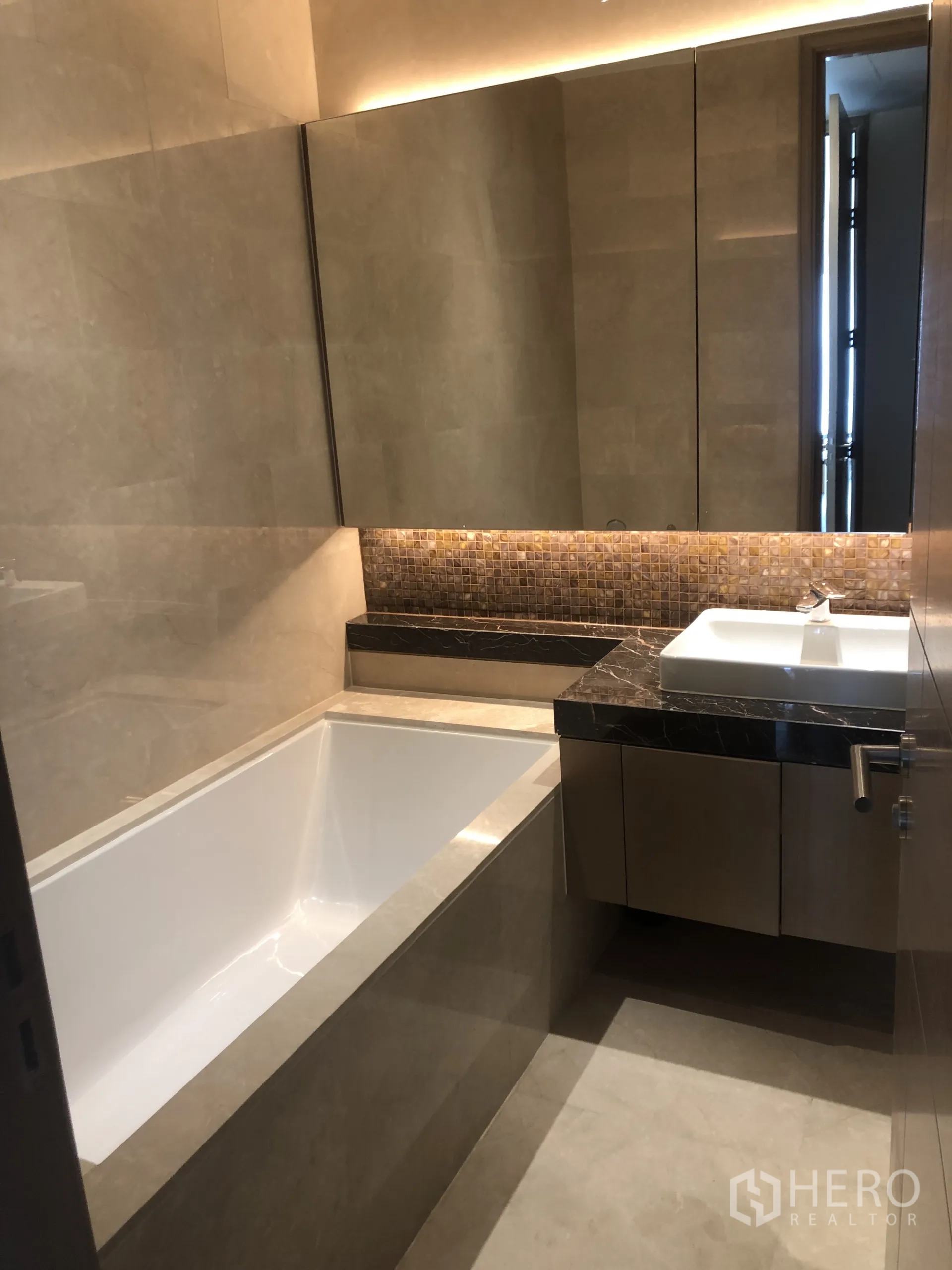 คอนโด ให้เช่าในPathum Wan, Bangkok - ห้องน้ำพร้อมอ่างอาบน้ำลึก เคาน์เตอร์หินอ่อน และตู้กระจกบานใหญ่แสงอบอุ่น.