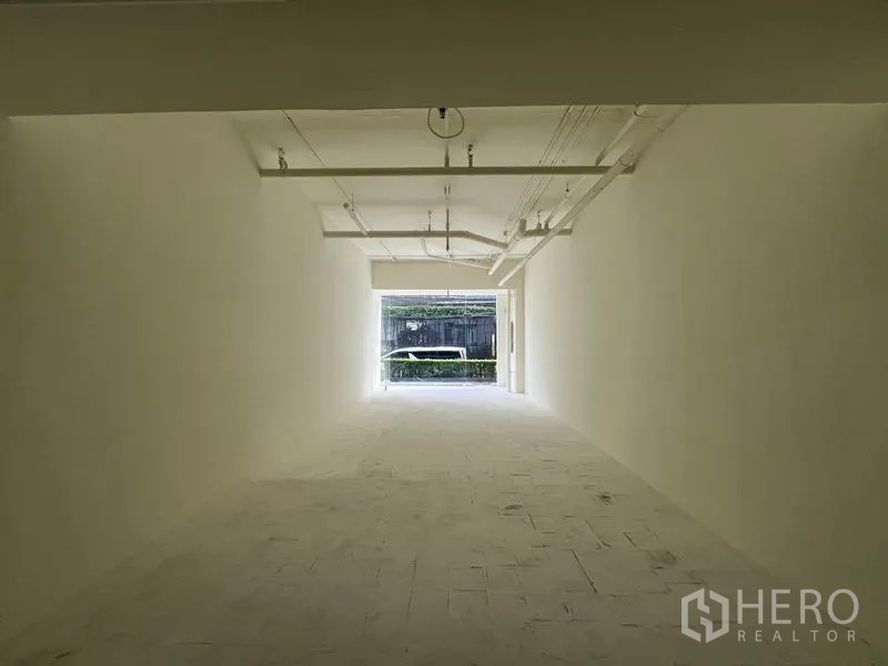 零售空间 出租在Watthana, Bangkok - 从后部望向玻璃立面，可见街侧绿篱景观。