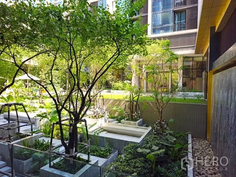 Condominium for rent or sale in Pathum Wan, Bangkok - Lush courtyard garden with tiered planters, water feature, and mature trees.