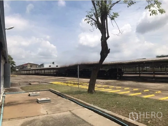 工厂 出租在Bang Bua Thong, Nonthaburi - 宽阔的硬化场地，长条形带顶雨棚和交通标线。