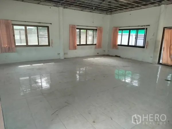 Detached House for rent or sale in Bang Na, Bangkok - Spacious empty interior room with tiled floor, multiple windows and exposed ceiling grid ready for renovation.