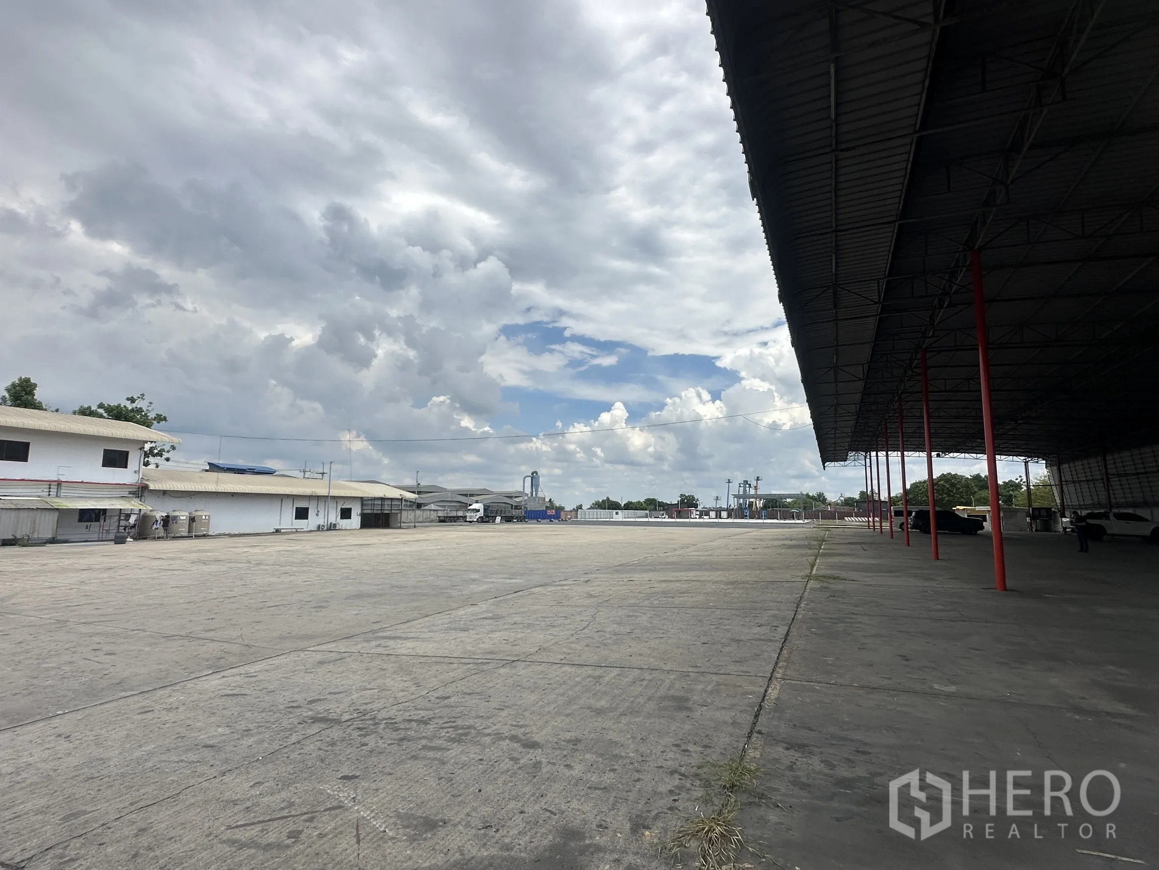 Land for rent in Wang Noi, Phra Nakhon Si Ayutthaya - Large paved yard next to a roofed shed and low-rise warehouses.