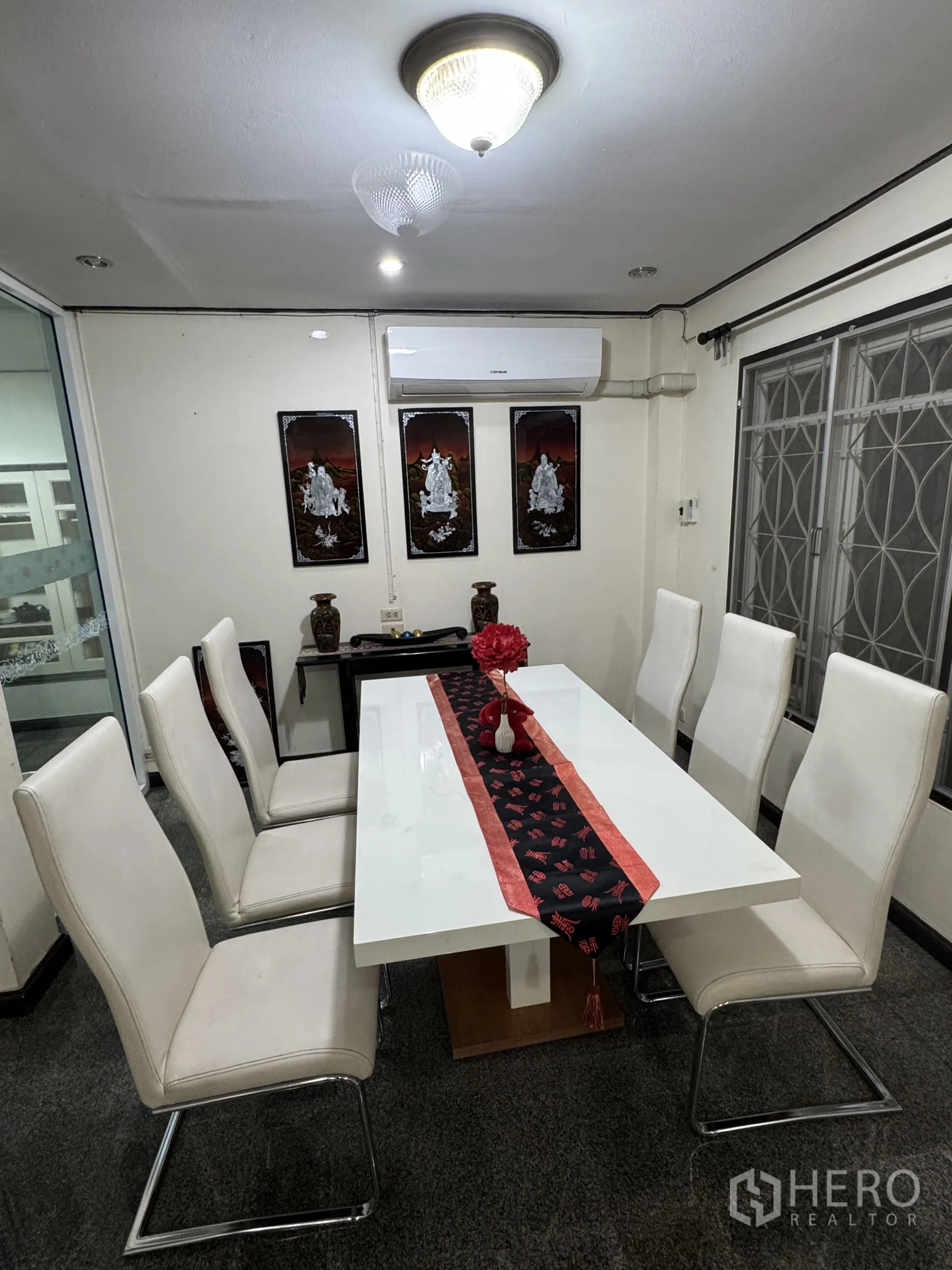 บ้าน ให้เช่าในMin Buri, Bangkok - มุมรับประทานอาหารโต๊ะสีขาว 8 ที่นั่ง พร้อมงานศิลป์ติดผนังและเครื่องปรับอากาศ