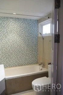 Condominium for rent in Pathum Wan, Bangkok - Bathroom featuring bathtub, mosaic accent wall and a small window.