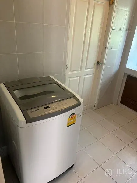 Detached House for rent in Bang Phli, Samut Prakan - Tiled laundry room with a top-load washing machine beside a bathroom door.