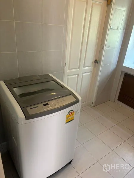 Detached House for rent in Bang Phli, Samut Prakan - Tiled laundry room with a top-load washing machine beside a bathroom door.