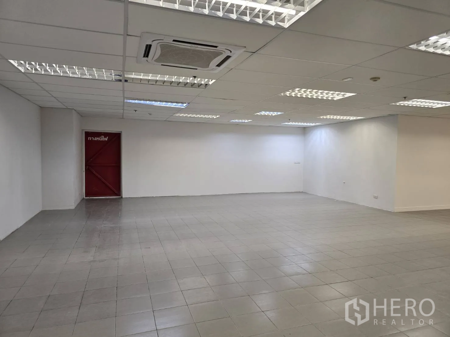 Retail Space for rent in Watthana, Bangkok - Open retail area with gray floor tiles, white walls, and a red fire-exit door.