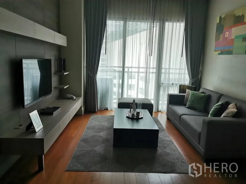 公寓 出租在Khlong Toei, Bangkok - 曼谷空堤区公寓现代客厅，灰色沙发、电视墙、茶几与落地窗阳台