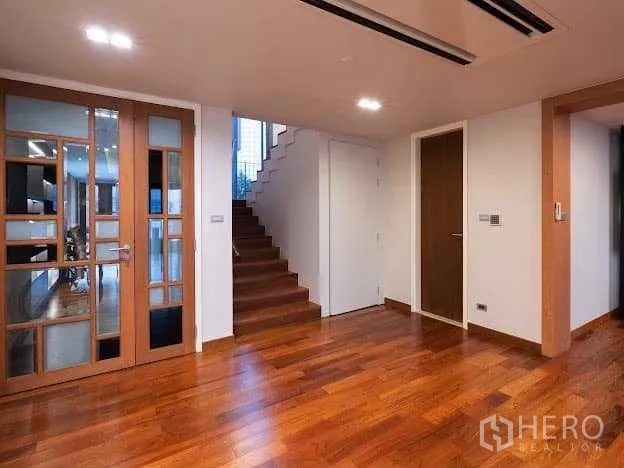 Condominium for sale in Yan Nawa, Bangkok - Foyer with glass‑panel doors and staircase leading to the upper level, set on hardwood floors.