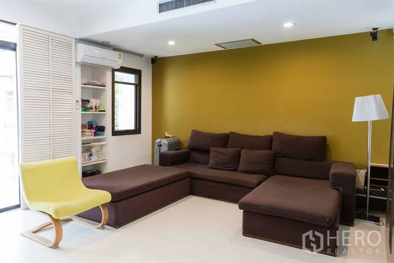 联排别墅 出售 - 客厅配棕色转角沙发、绿色强调墙与筒灯。