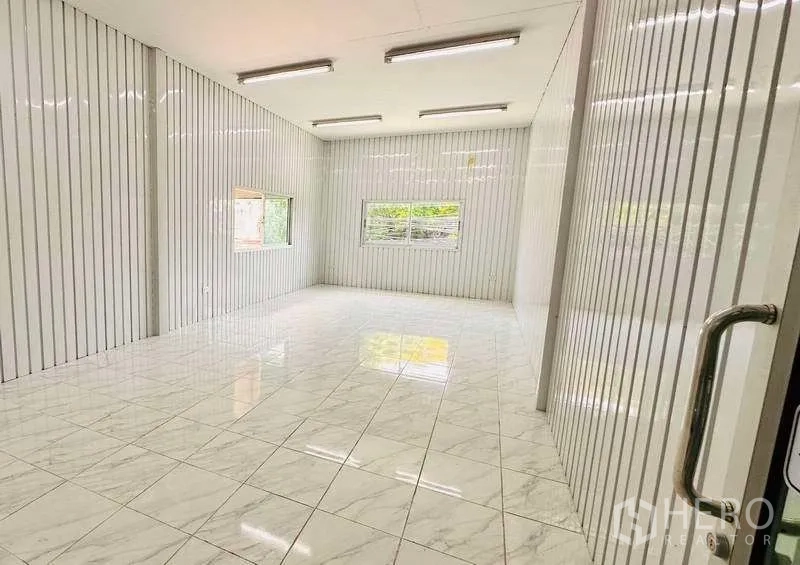 Warehouse for rent in Pak Kret, Nonthaburi - Bright office space with white panel walls, windows and LED ceiling lights.