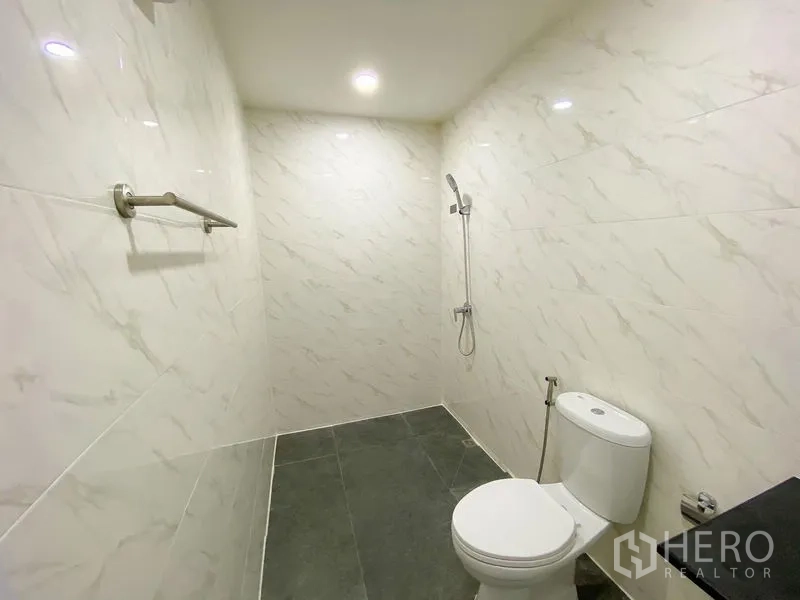 带办公室的家 出租或出售在Bang Na, Bangkok - 卫生间铺大理石纹墙砖，步入式淋浴与坐便器。