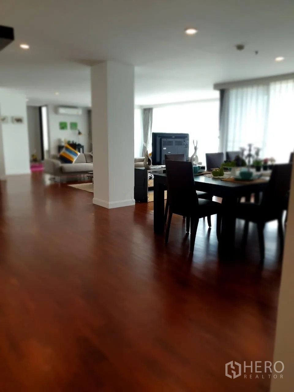 Apartment for rent in Bang Rak, Bangkok - Open-plan view to eight-seat dining table and living area with large windows.