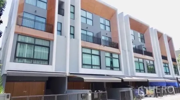 Townhouse for rent or sale in Suan Luang, Bangkok - Row of modern townhouses with cantilevered facades and covered carports.
